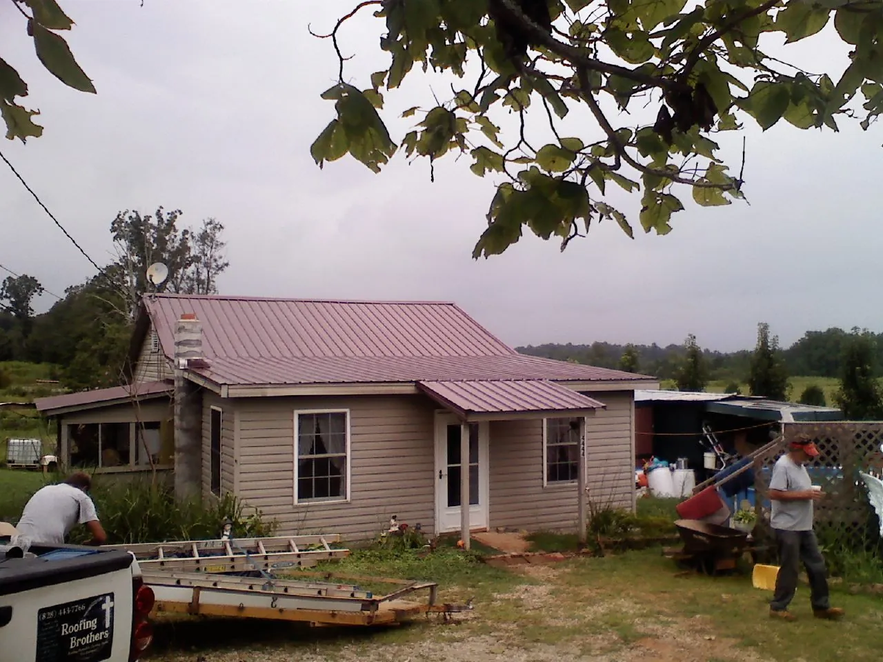 Crew finishing a mauve metal roof on a small farmhouse in Hillsboro
